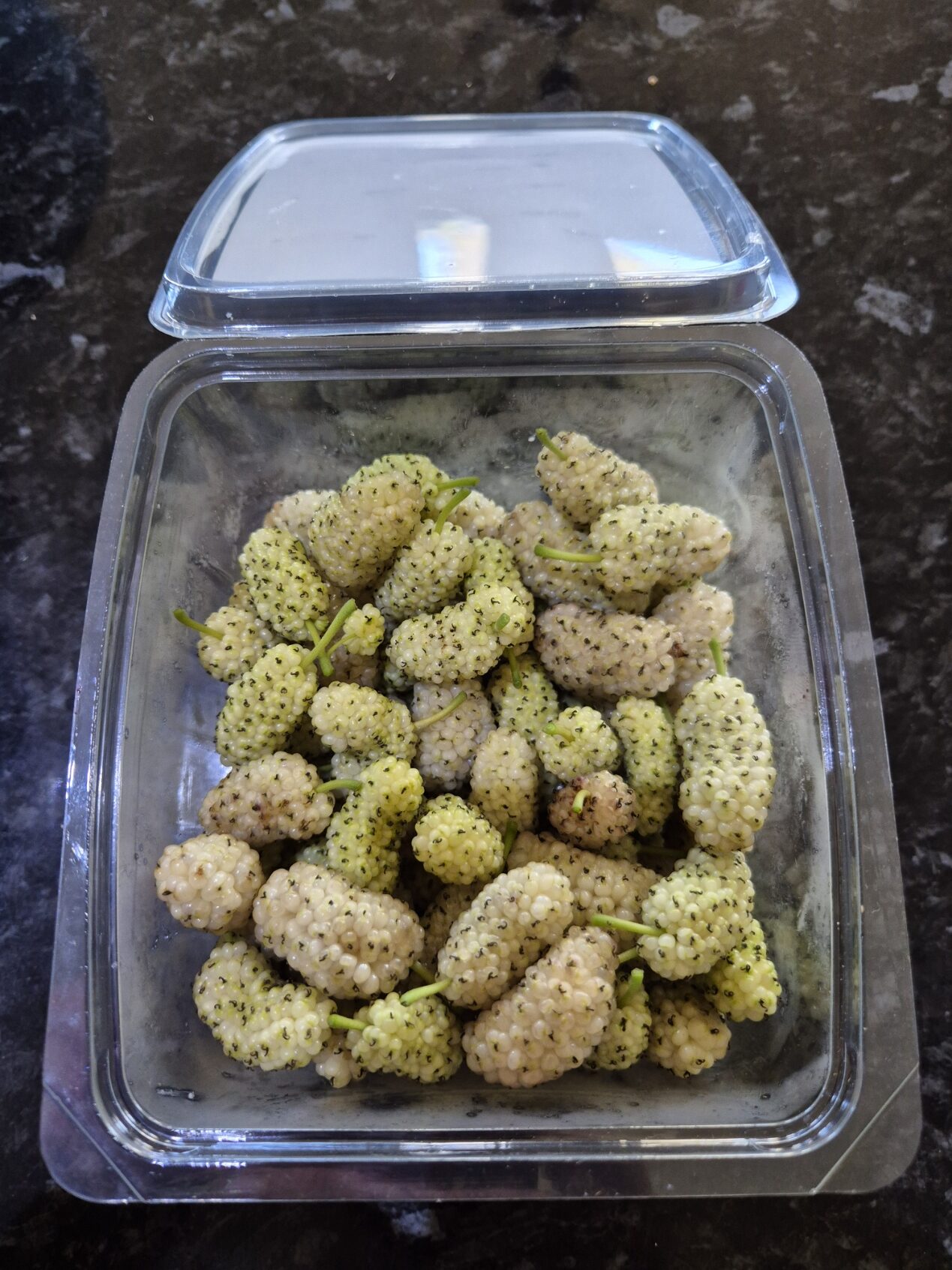 A punnet of pale white mulberries freshly picked